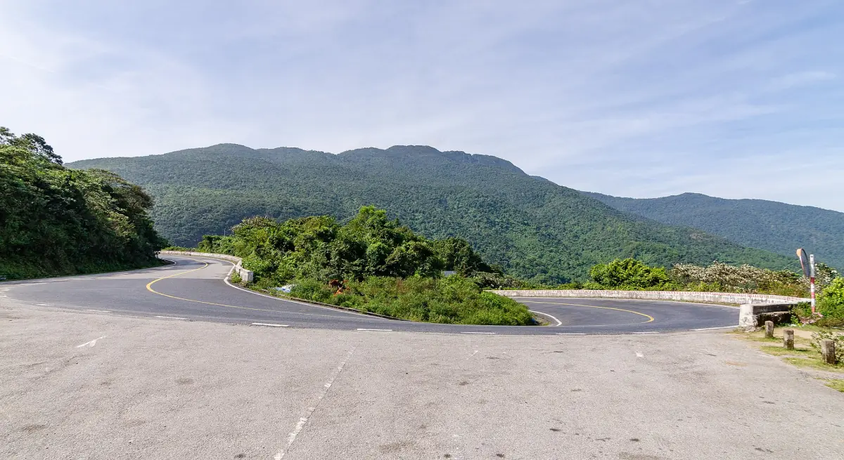 Mountain road bending around a ridge with green hills