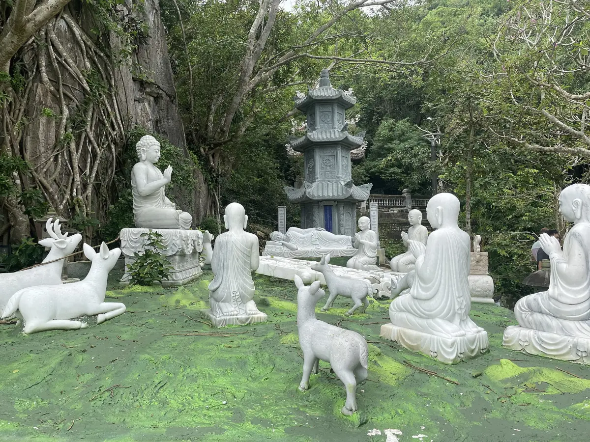 White Buddha statues and a small pagoda in a green garden