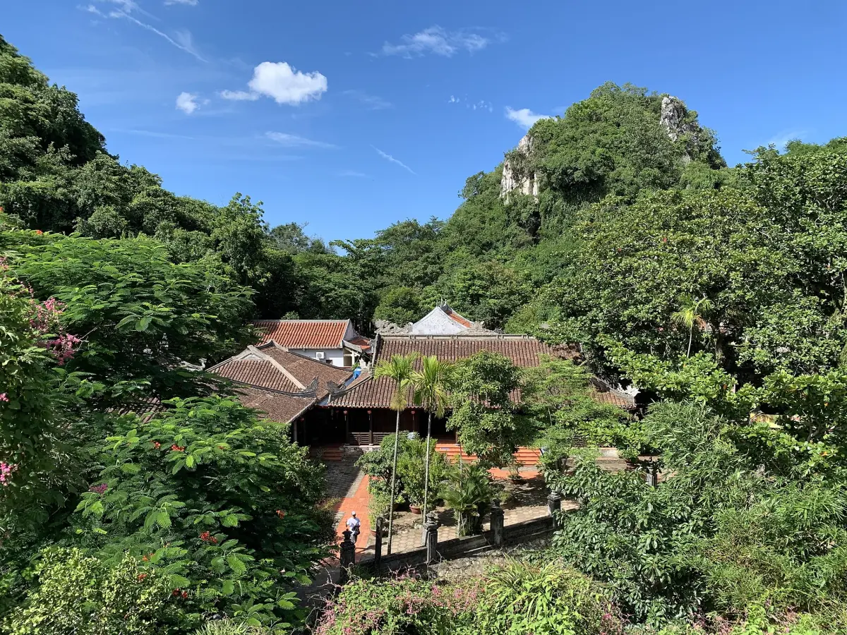Temple roofs among green limestone hills under a blue sky