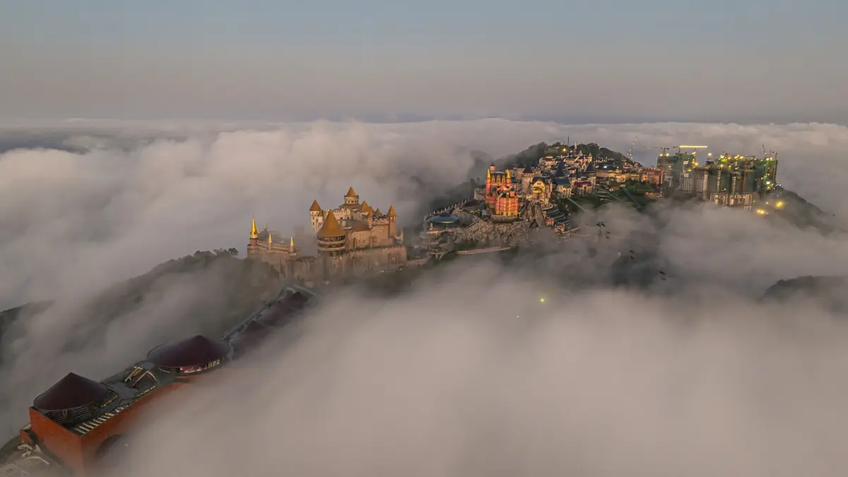 Mountain top buildings emerging from a sea of clouds at dawn