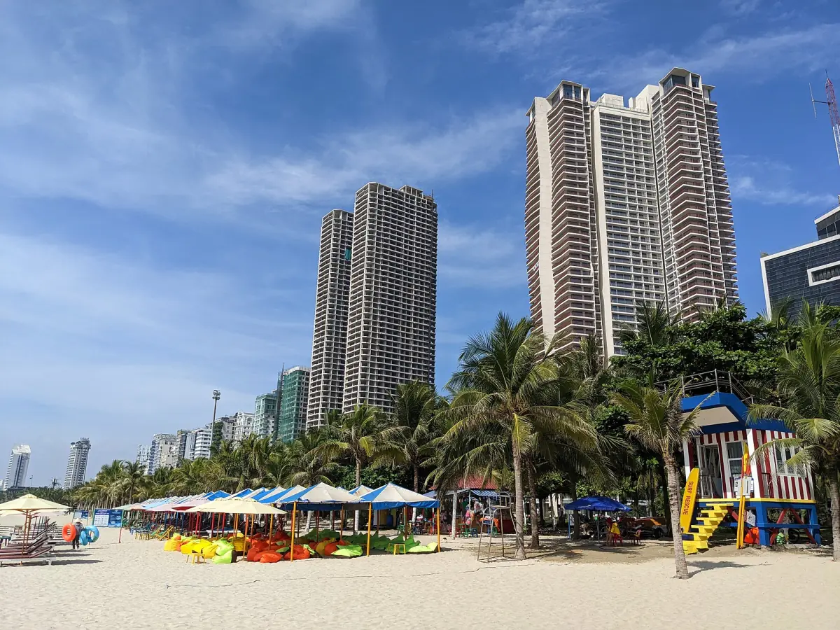 Sandy beach with beach umbrellas and high-rise buildings behind