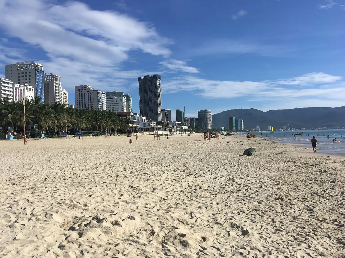 寬闊沙灘沿著海灣延伸,遠處是城市天際線