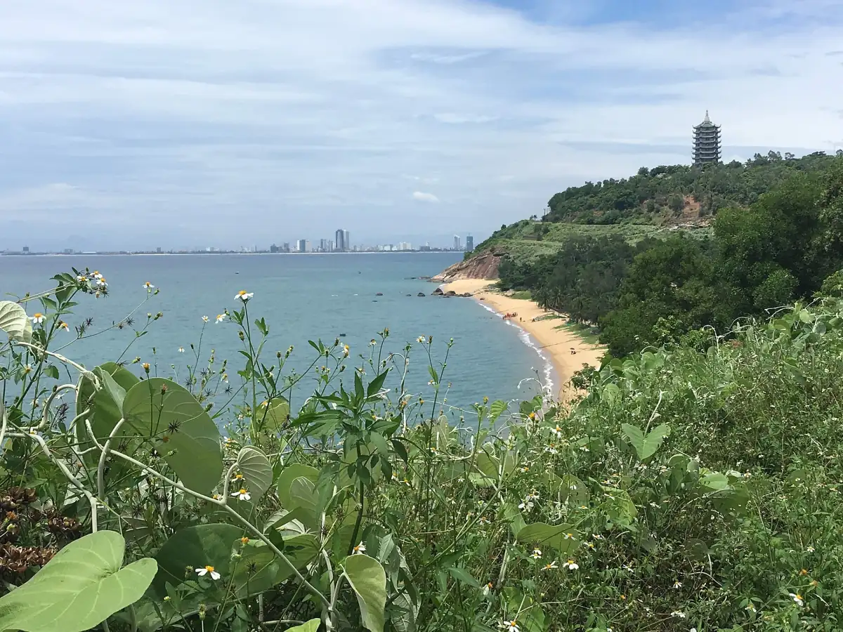 海灣上方綠樹覆蓋的岬角,有一片小海灘和一座寶塔